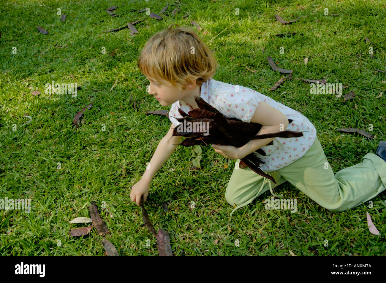 Spagna Andalusia Siviglia Parco Maria Luisa Bambina ammassare le foglie Foto Stock