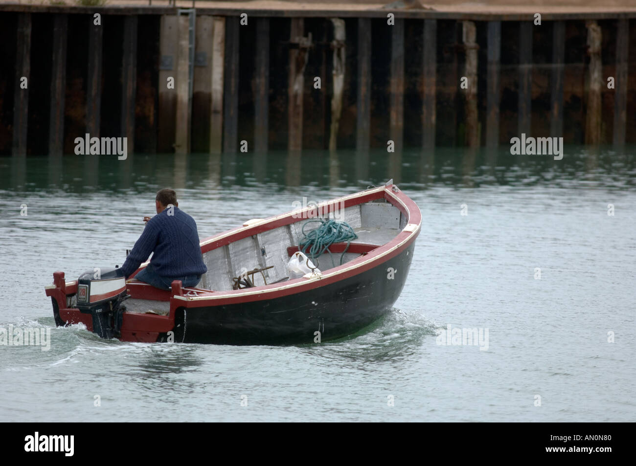 Uomo in una piccola barca di gara in un estuario Foto Stock