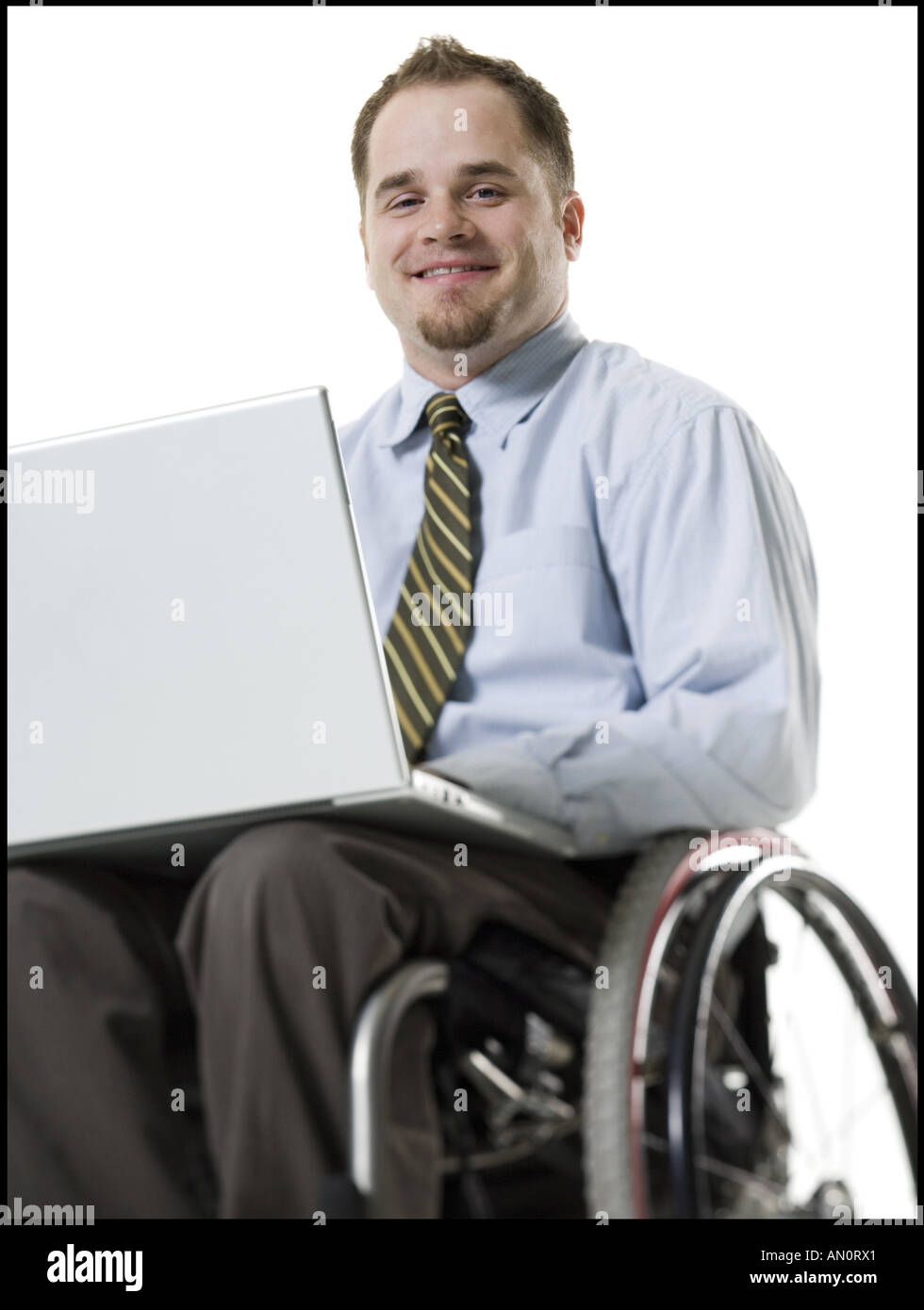 Ritratto di un giovane uomo seduto in una sedia a rotelle usando un computer portatile Foto Stock