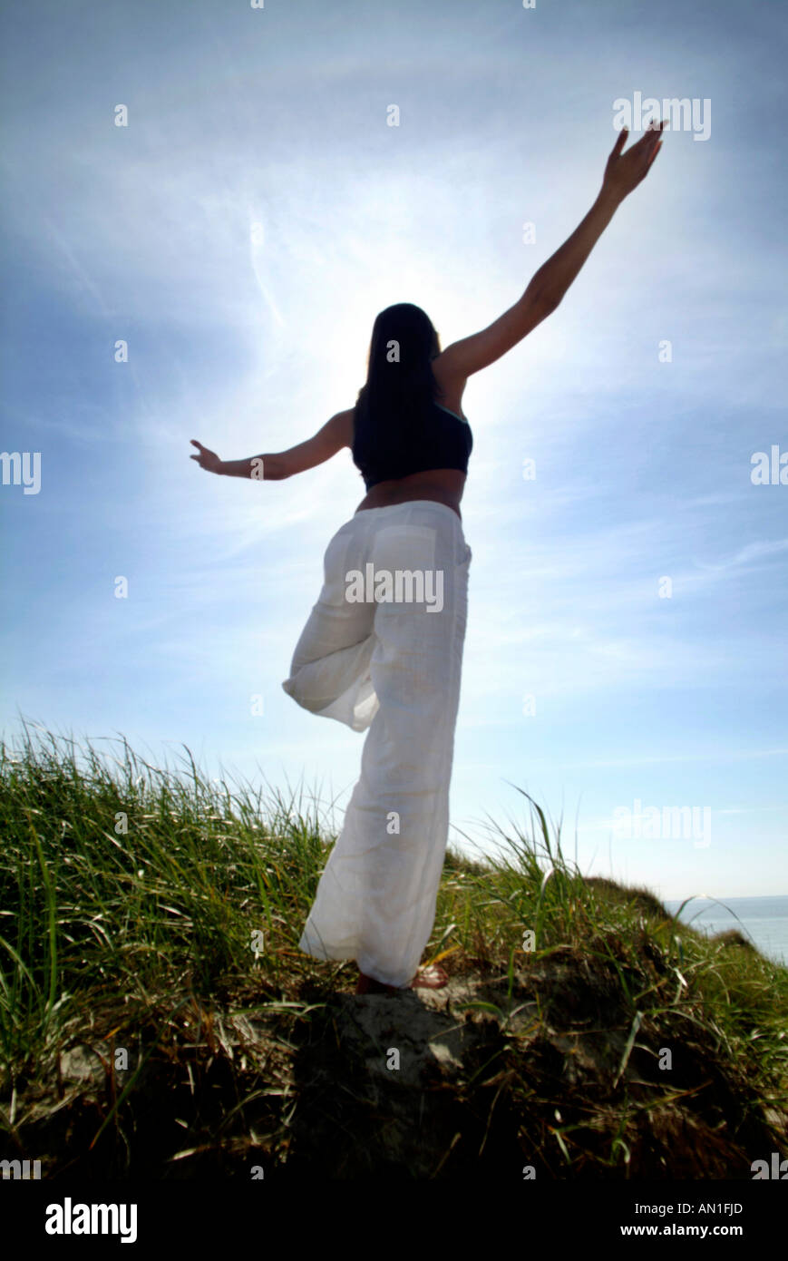 Giovane donna facendo un esercizio di Yoga al mare Foto Stock