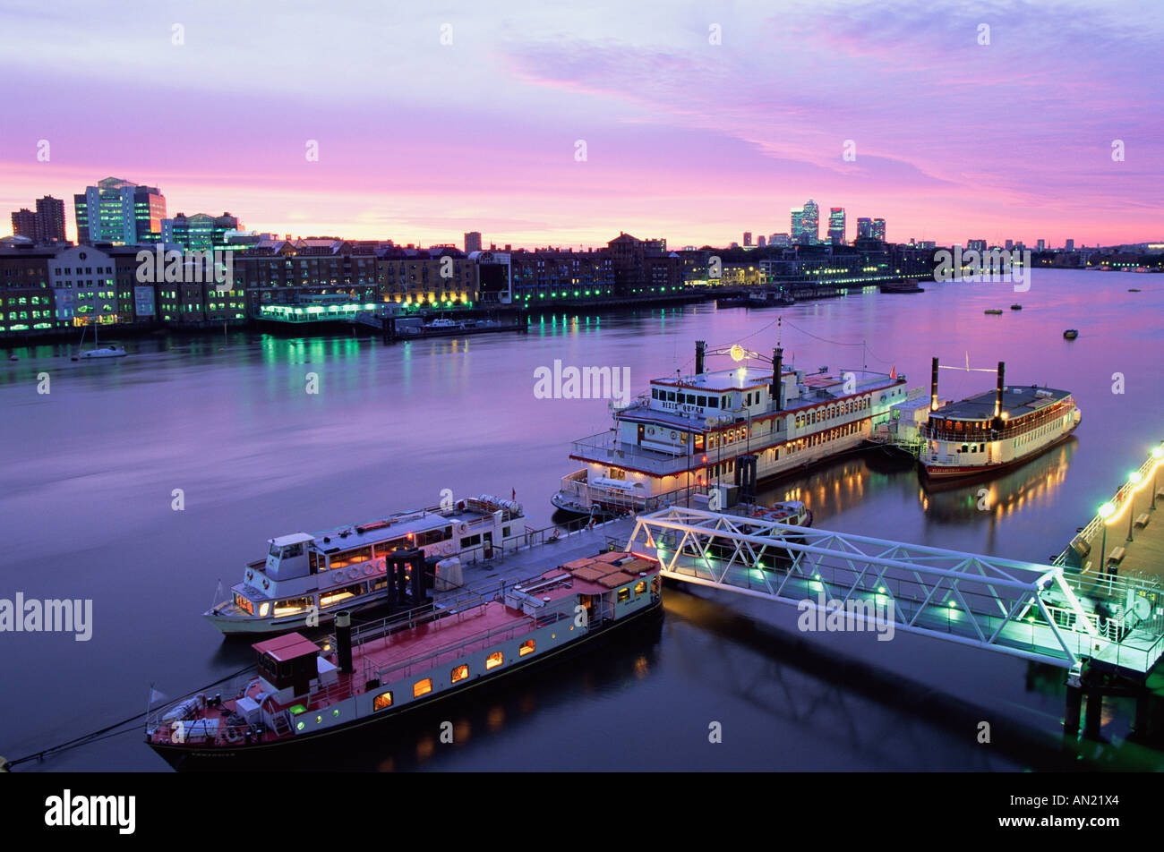 Inghilterra, Londra, vista notturna di barche sul Fiume Tamigi con Docklands e da Canary Wharf Skyline in background Foto Stock