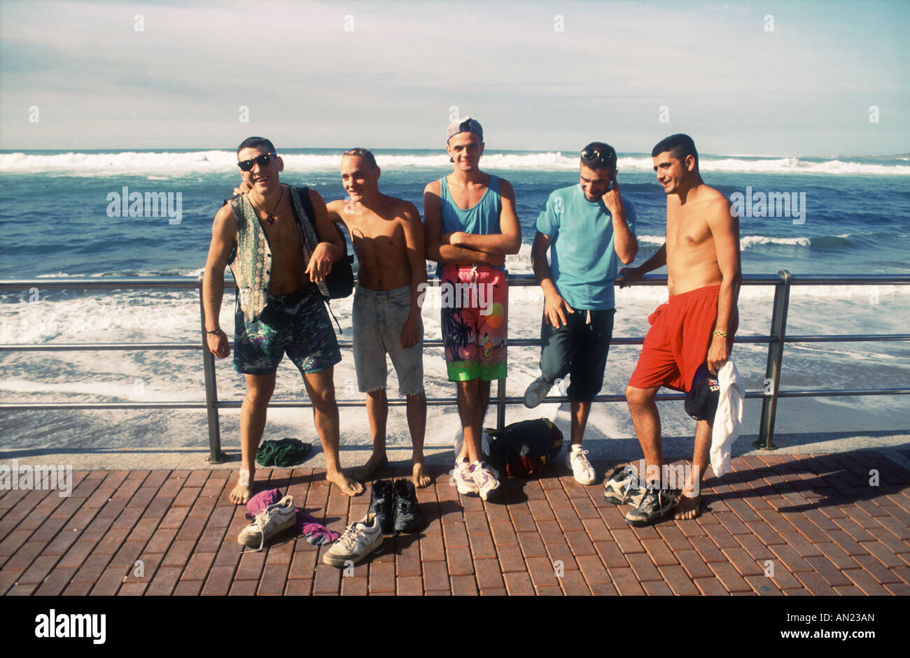 Giovani uomini in piedi sul lungomare di spiaggia Las Canteras, Las Palmas, Gran Canaria Isole Canarie. Foto Stock