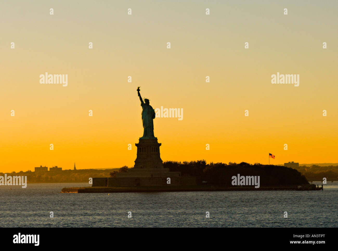 La città di New York skyline al tramonto con la Statua della Libertà silhouette e la bandiera americana. Foto Stock