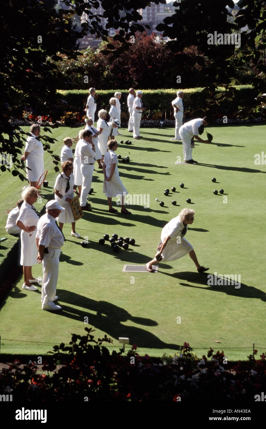 Uomini e donne che gareggiano nel Lawn Bowls si affrontano su un campo da bowling con una splendida vista dall'alto sulla soleggiata Guildford, Surrey, Inghilterra, Regno Unito Foto Stock