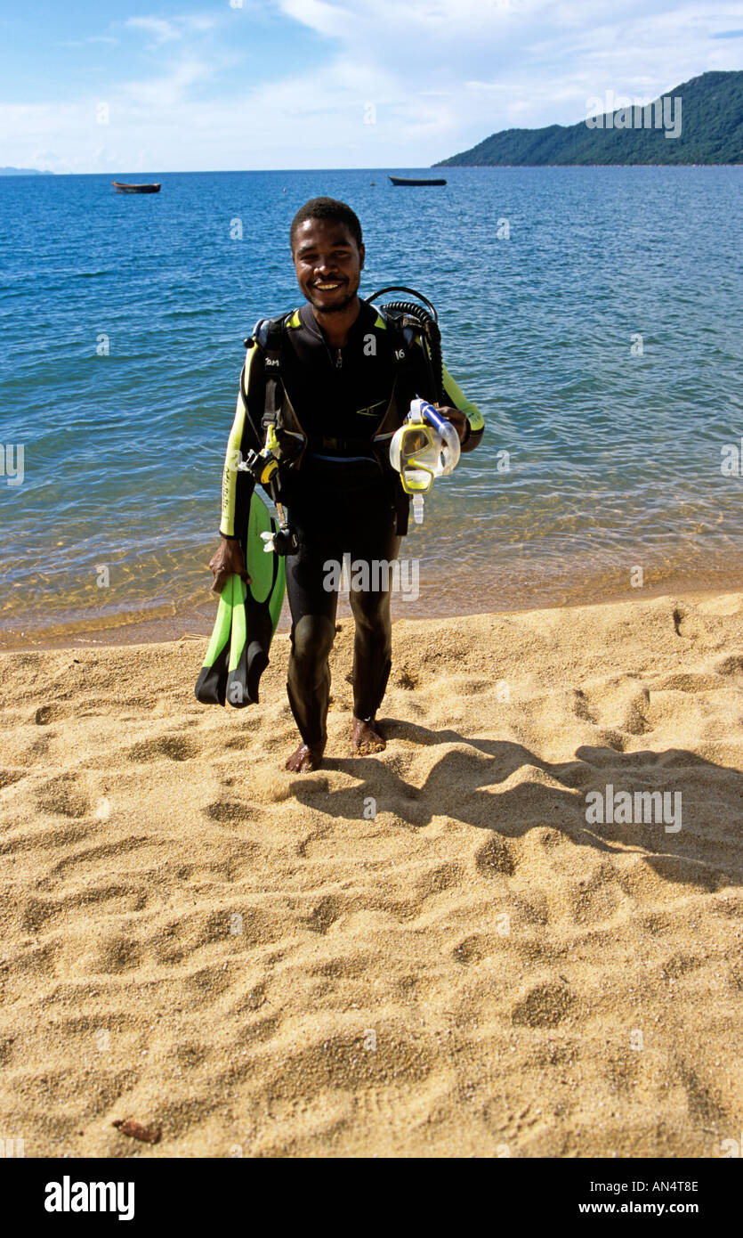 Un africano sub in piedi su una spiaggia tenendo il suo equipaggiamento Foto Stock