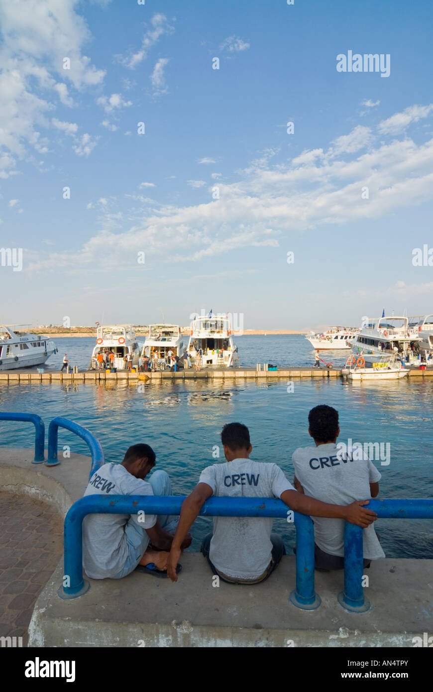 I giovani egiziani la visione di barche per immersioni ritorno dal viaggio in giornata, Naama Bay, a Sharm el Sheikh, Egitto Foto Stock
