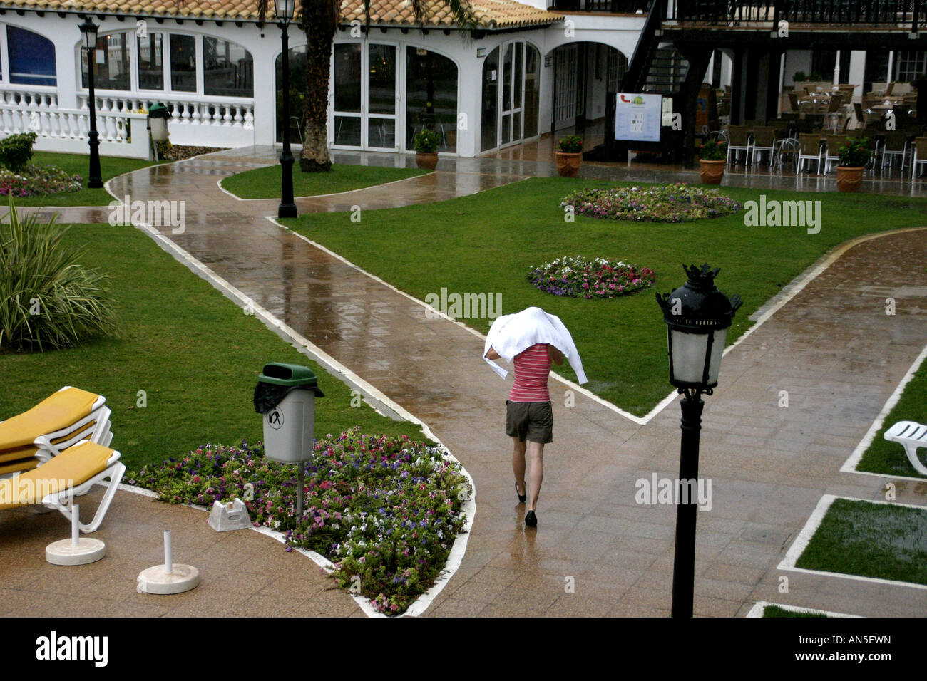 Un guest in esecuzione per coprire durante pioggia pesante in un hotel in Menorca Foto Stock