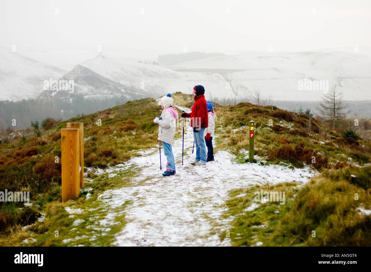 Una madre e le sue due giovani figlie a Nant Yr ariano centro foresta Ponterwyd , inverno nella neve, Wales UK Foto Stock