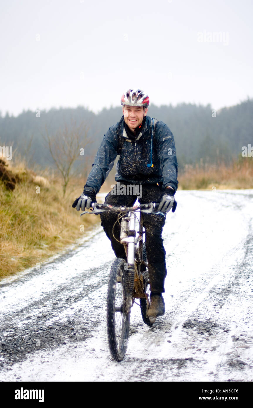 Un uomo maschio mountain biker Nant Yr arian Forest park vicino a Aberystwyth Ceredigion gennaio neve invernale, Wales UK Foto Stock