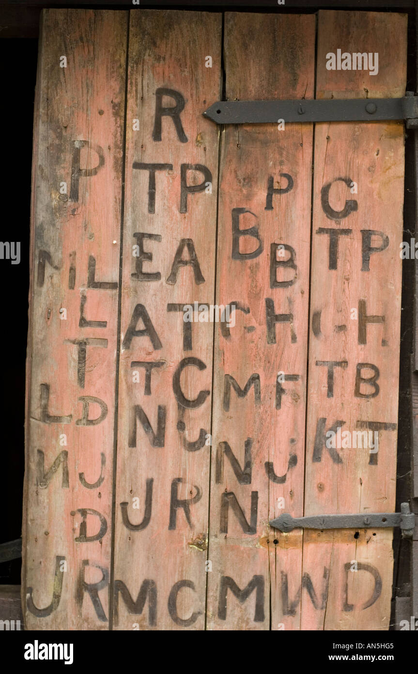 Persiane di legno sul vecchio fabbro Penybont shop Powys Galles, con segni di marca di lettere e simboli Foto Stock