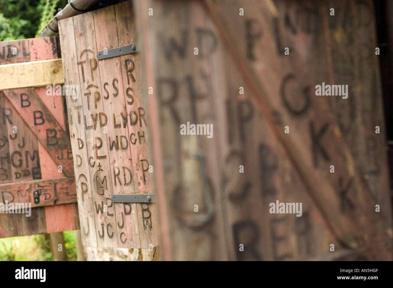 Persiane di legno sul vecchio fabbro Penybont shop Powys Galles, con segni di marca di lettere e simboli Foto Stock