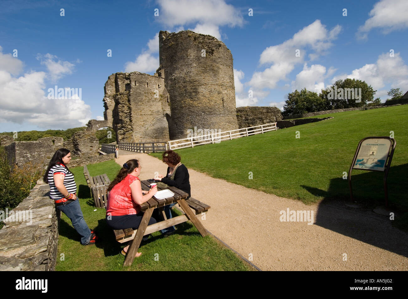 Tre persone sedute a un picnic al di fuori del banco Cilgerran Castle pembrokeshire west wales pomeriggio estivo Foto Stock