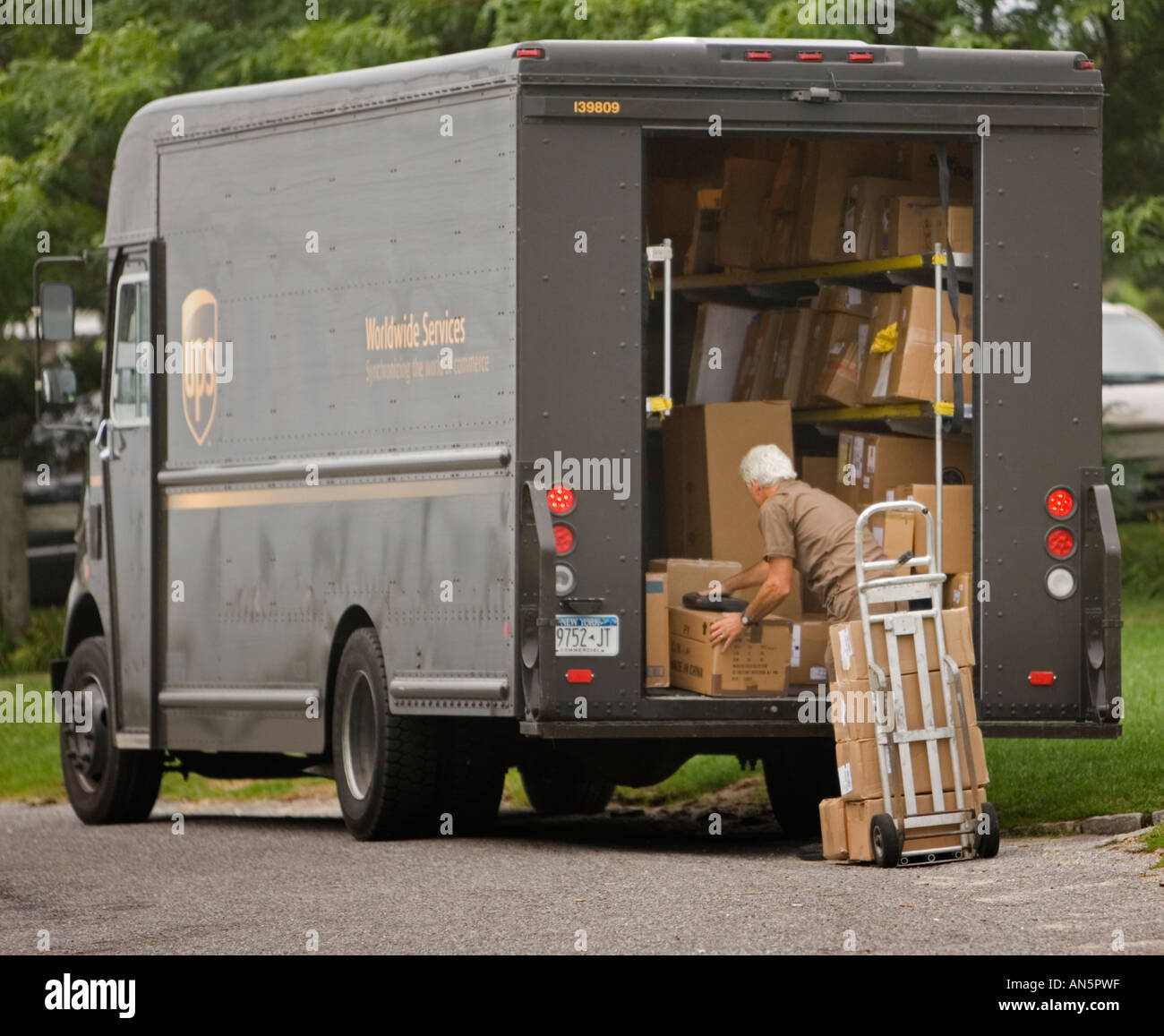 Lavoratore scarico delle confezioni da un carrello UPS Foto Stock