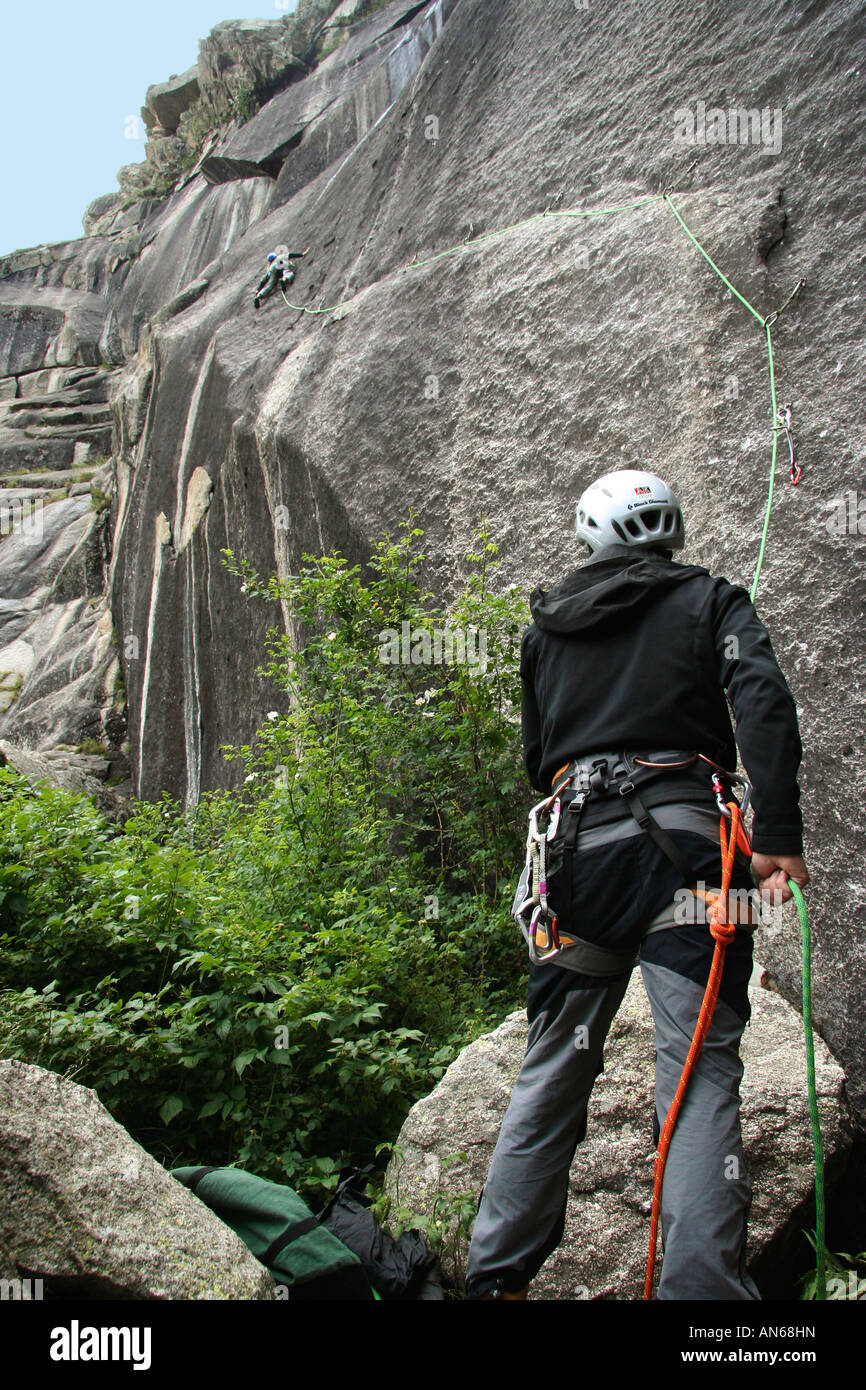 Rocciatore belaying scalatore di piombo in attraversamento di una lastra di granito, alti Pirenei, Spagna Foto Stock
