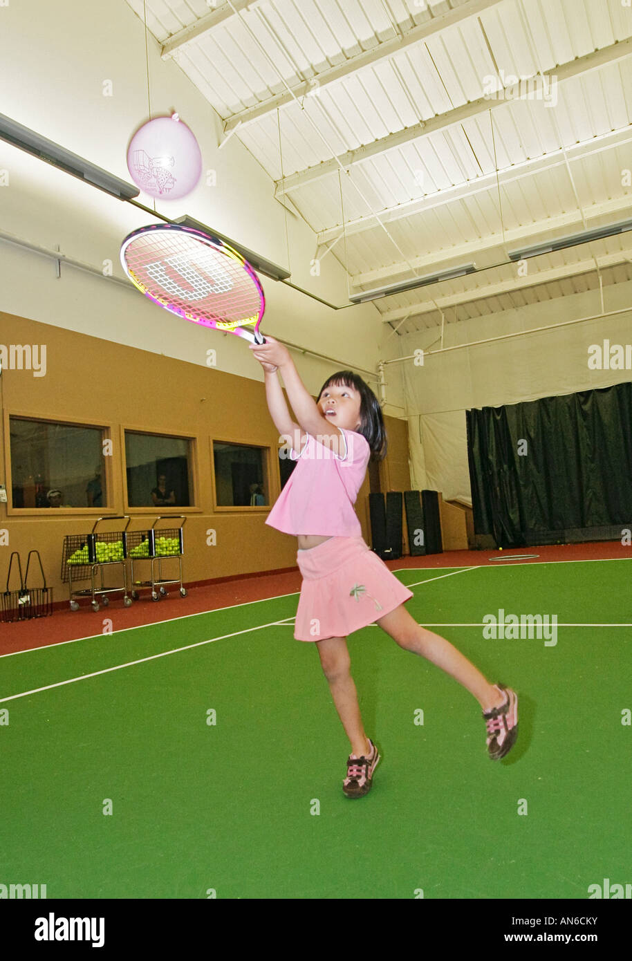 Bambini pratica di colpire un palloncino con la racchetta da tennis presso  palestra locale durante la classe volti a pre teens Foto stock - Alamy