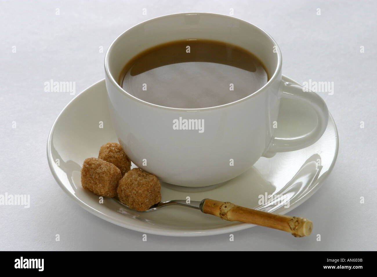 Il caffè con il latte in una tazza bianca e piattino con un cucchiaio Foto Stock