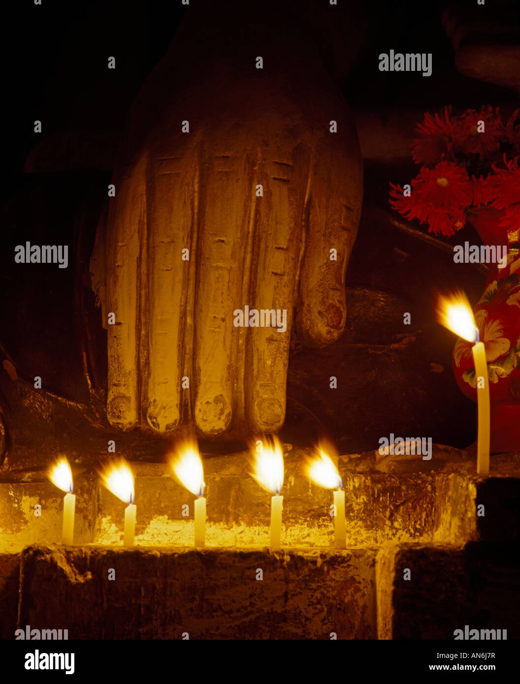 La mano di una statua del Buddha nella luce di candele Buddhahand im nächtlichen Kerzenlicht Foto Stock