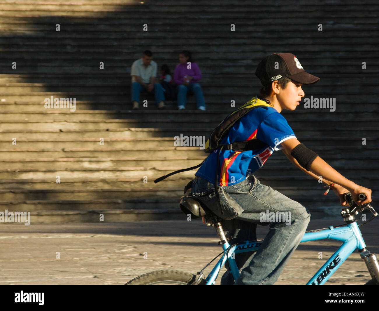 Messico Guanajuato Giovane ragazzo in Bicicletta Equitazione in plaza vicino Alhondiga giovane seduto sui gradini in ombra Foto Stock