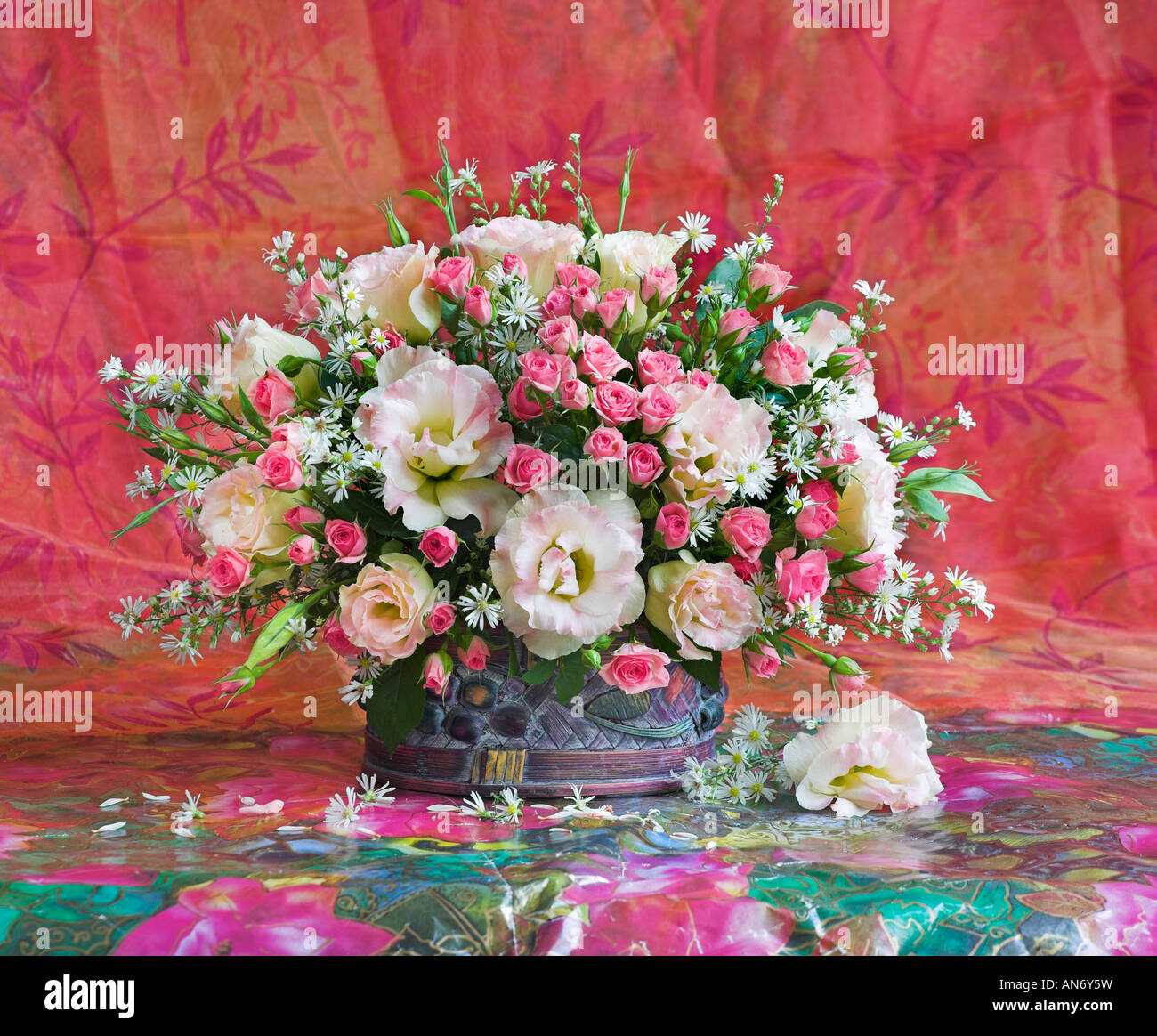 Studio disposti mazzetto bouquet di anemoni bianchi e rosa rose in cesto su un pastello sfondo rosso Foto Stock