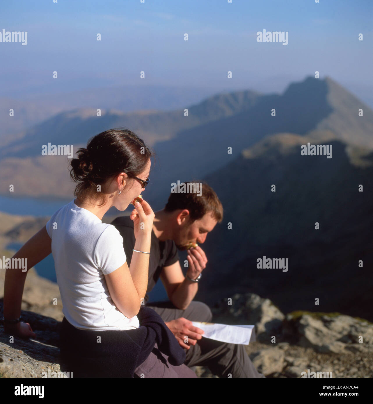 Gli escursionisti di mangiare le mele di prendere un periodo di riposo e guardando una mappa mentre si cammina fino a Mount Snowdon nella primavera del Parco Nazionale di Snowdonia Wales UK KATHY DEWITT Foto Stock