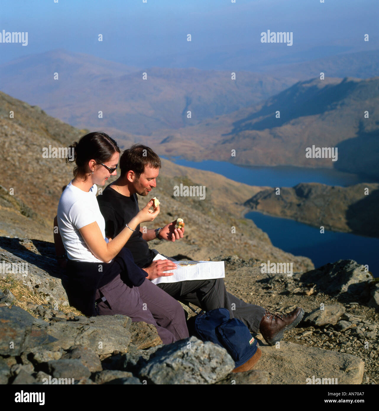 Gli escursionisti di mangiare le mele di prendere un periodo di riposo e guardando una mappa mentre si cammina fino a Mount Snowdon nella primavera del Parco Nazionale di Snowdonia Wales UK KATHY DEWITT Foto Stock