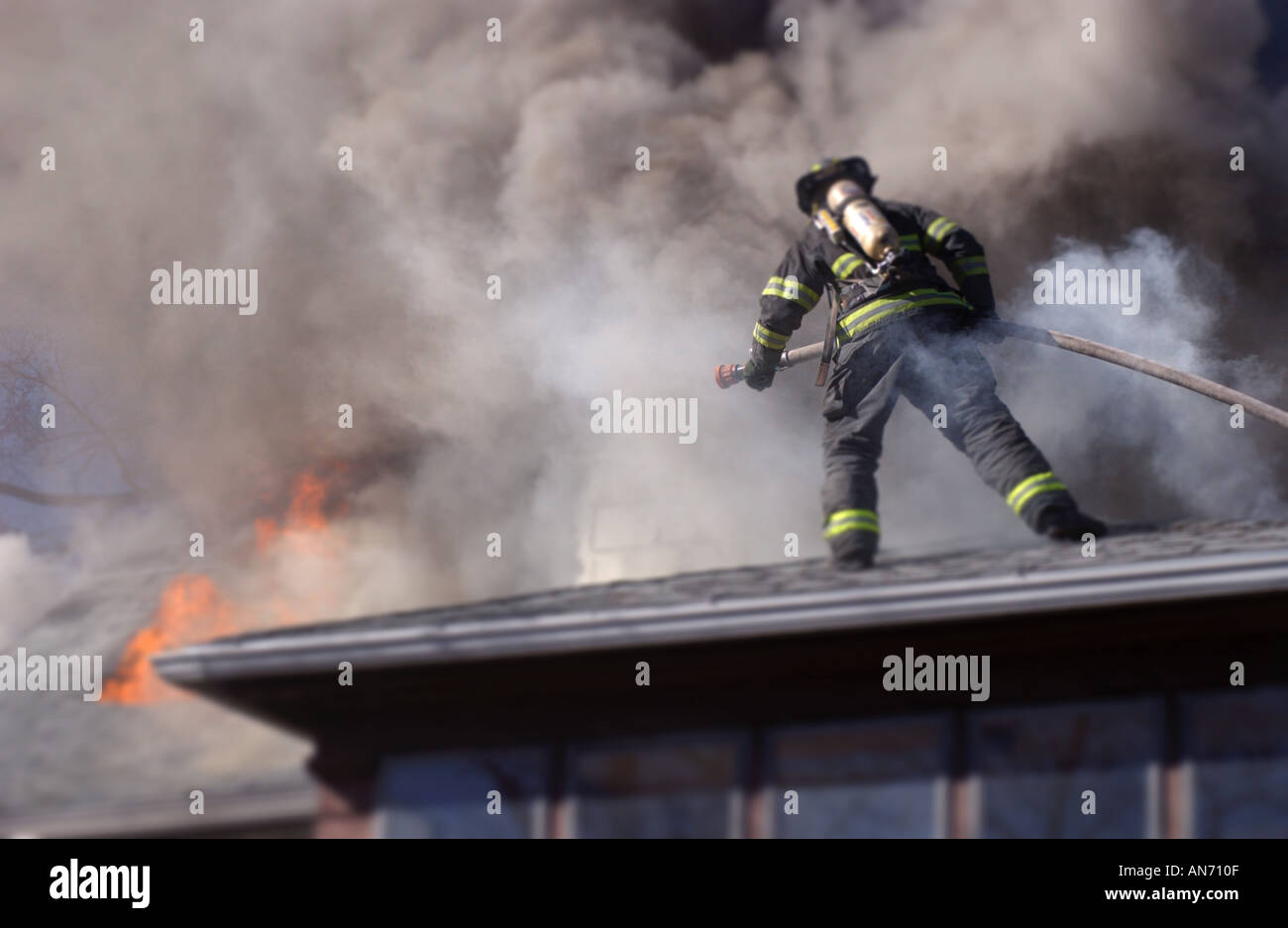 Vigile del fuoco su un tetto a combattere un incendio Foto Stock