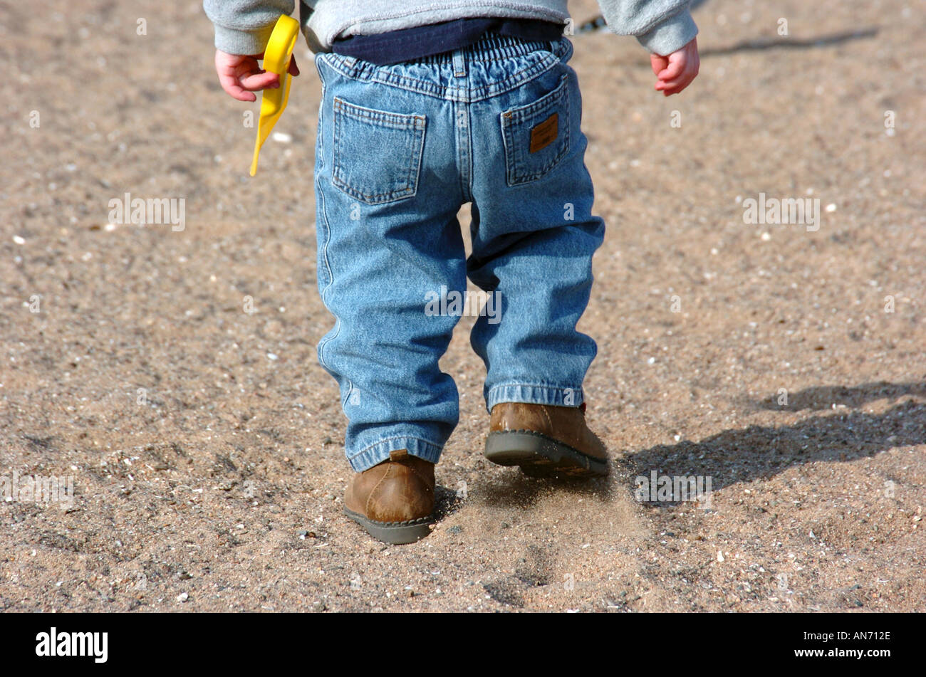 Bambino camminando sulla spiaggia con jeans sulla Foto Stock