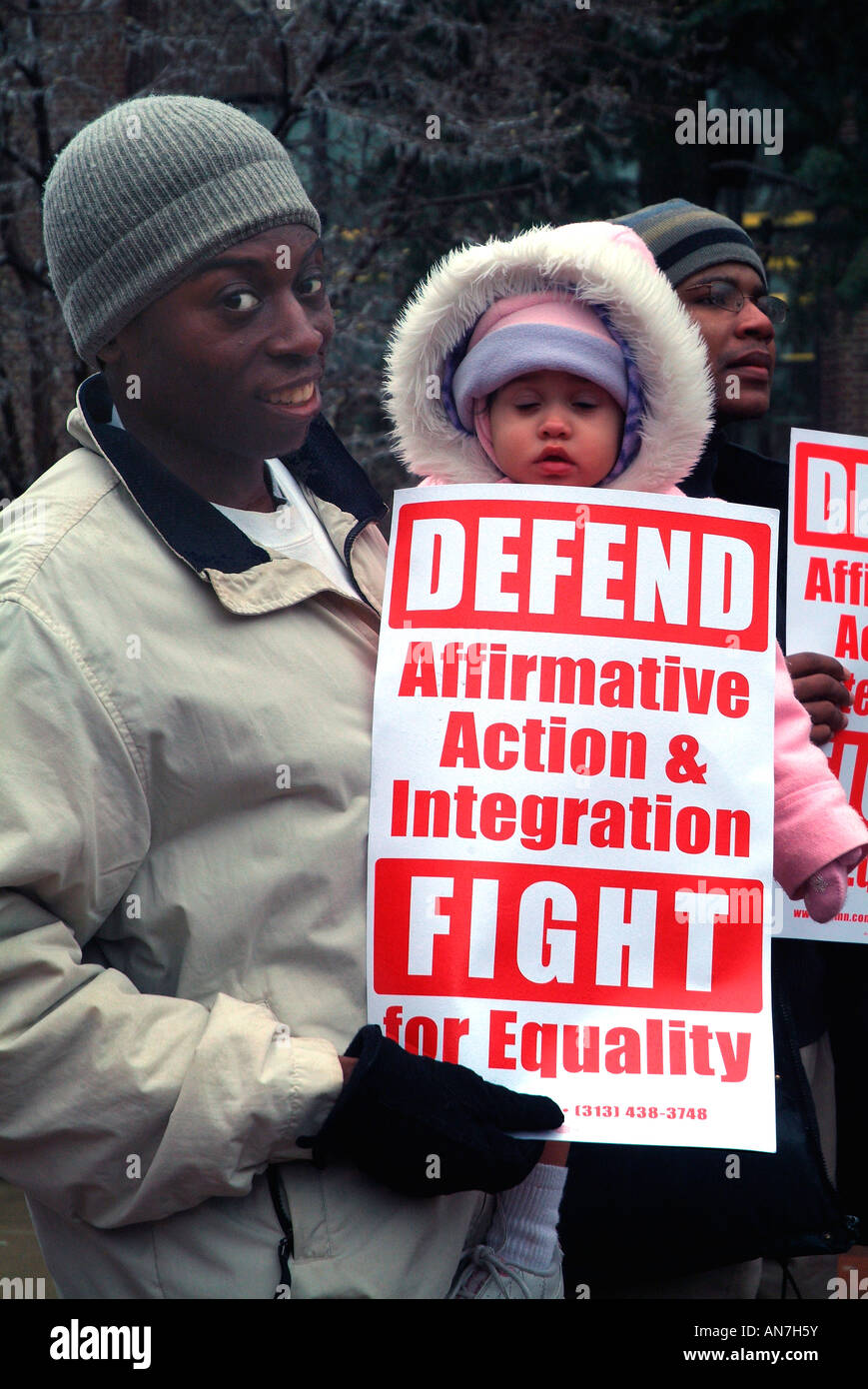 Una donna afro-americana e un baby fino in dotazione per il freddo. La donna tiene un segno per azione affermativa. Foto Stock