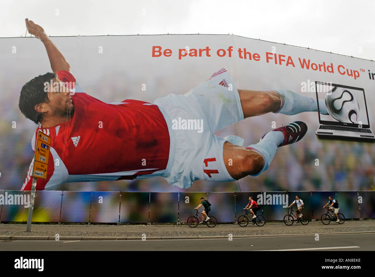 I ciclisti ride sotto molto grande cartellone pubblicitario del calciatore a Berlino Germania 2006 durante la World Cup Foto Stock