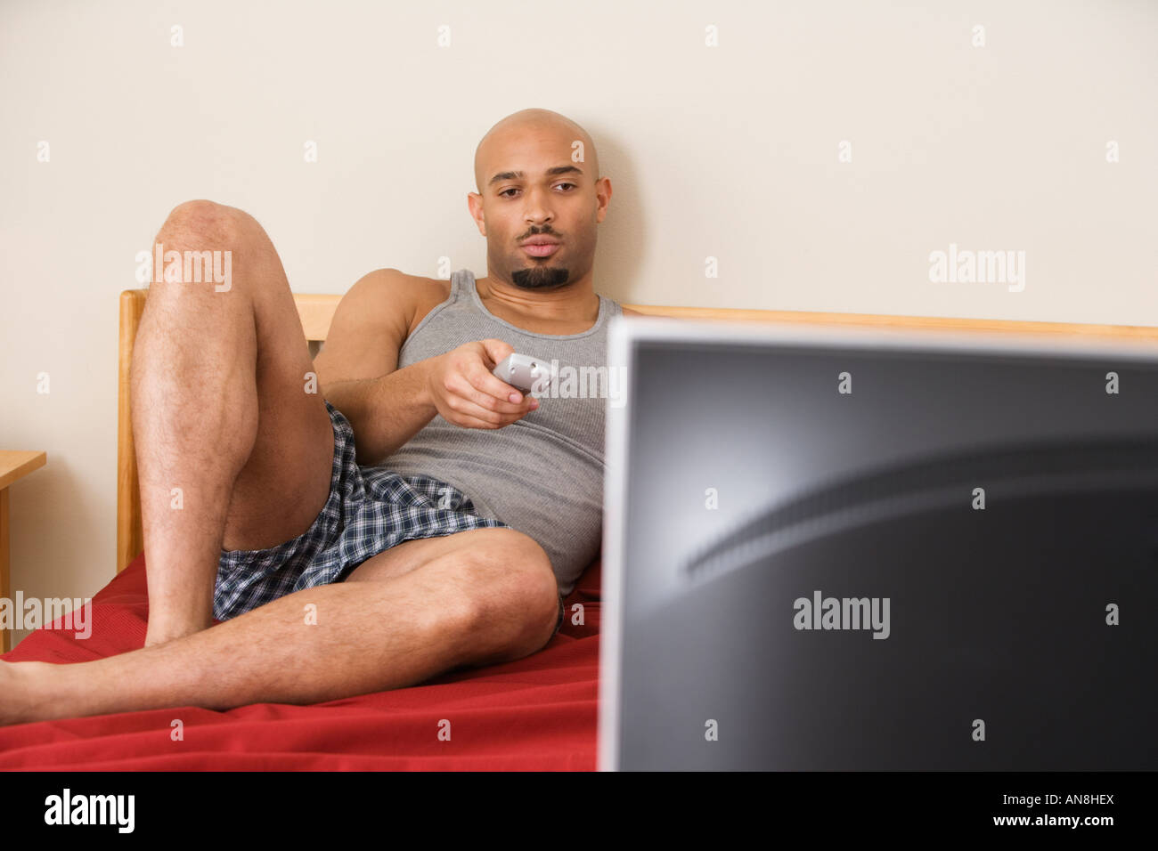 L'uomo africano di guardare la televisione a letto Foto Stock