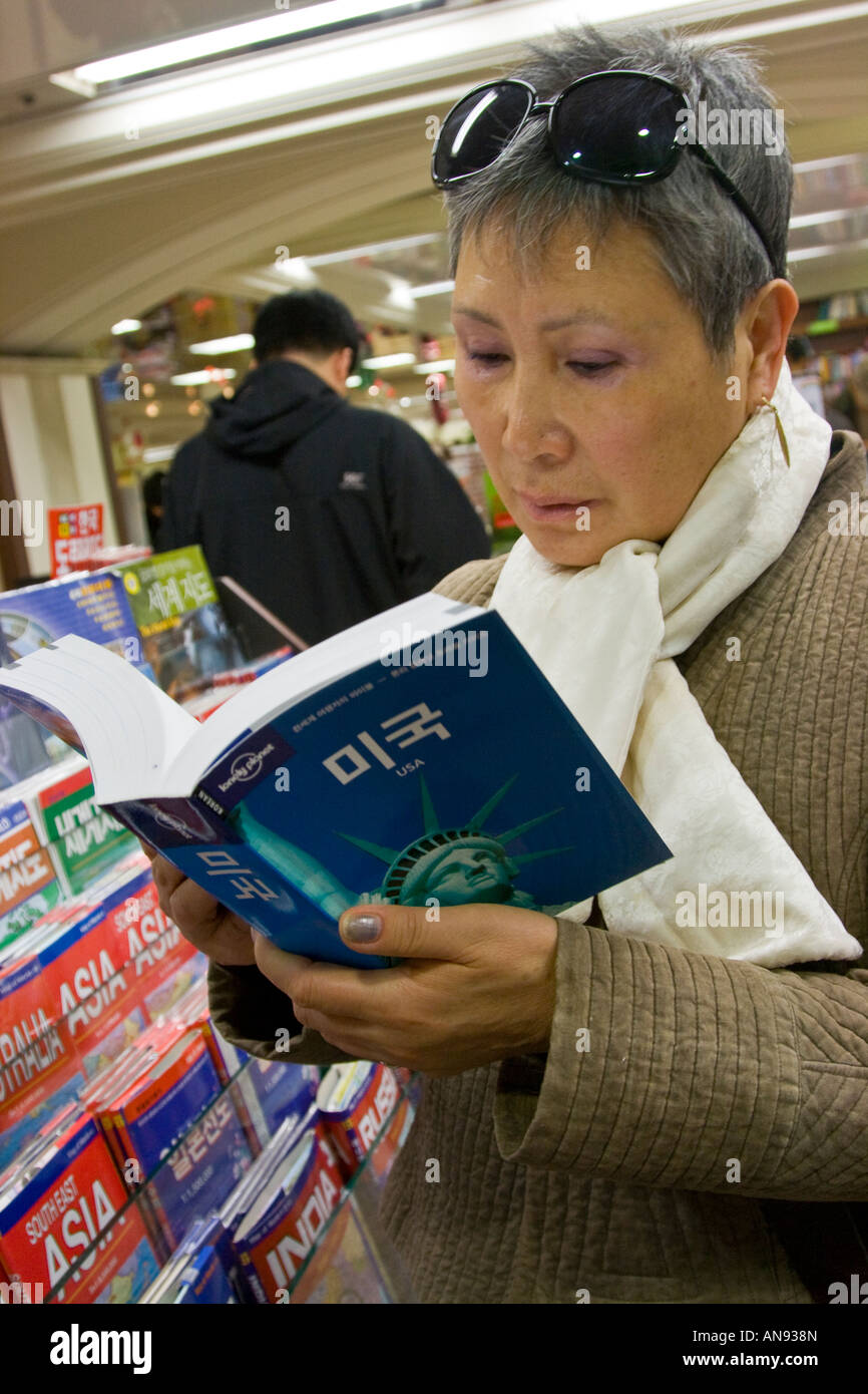 Donna coreana la lettura di un libro guida USA in una libreria Seoul COREA DEL SUD Foto Stock