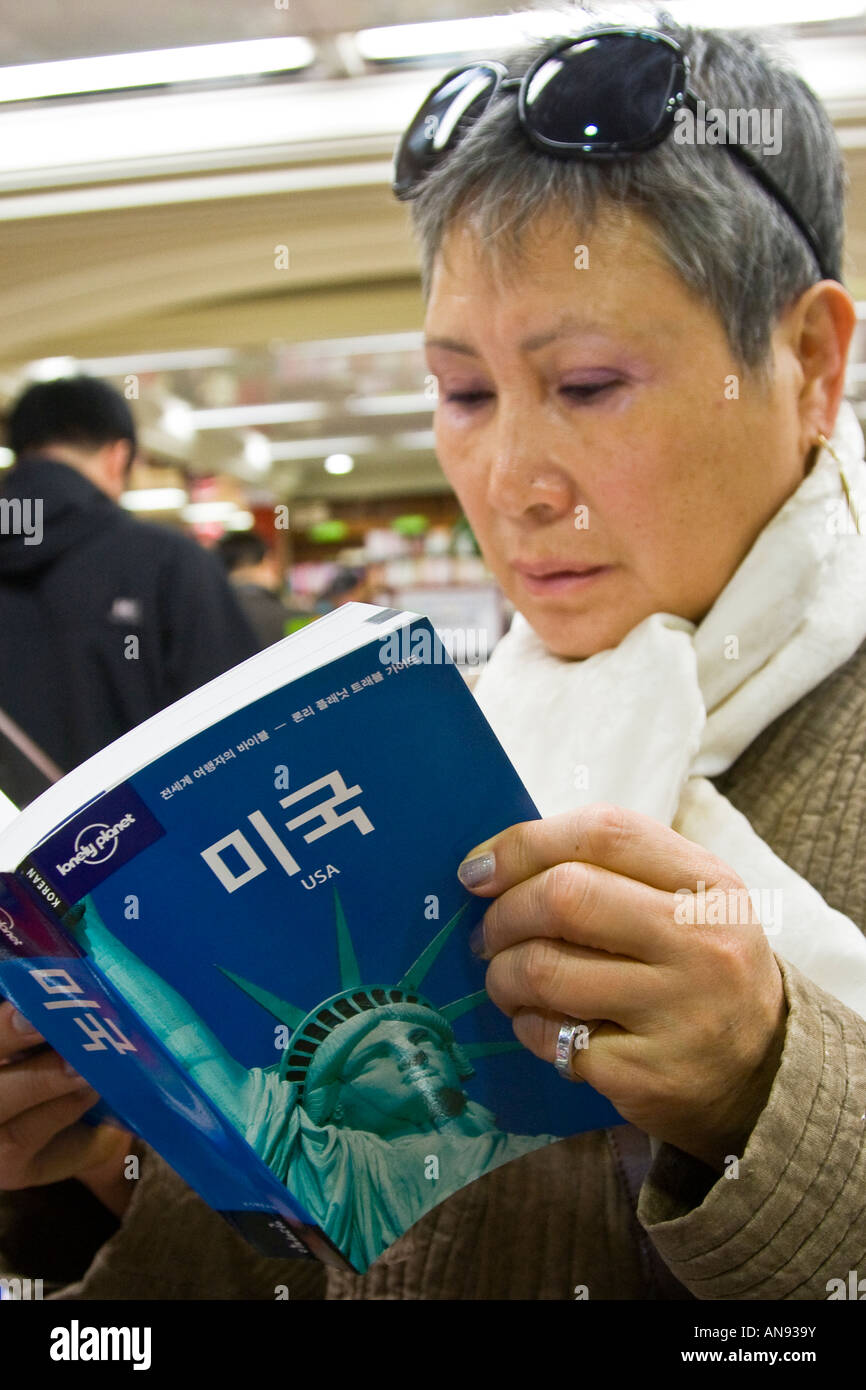 Donna coreana la lettura di un libro guida USA in una libreria Seoul COREA DEL SUD Foto Stock