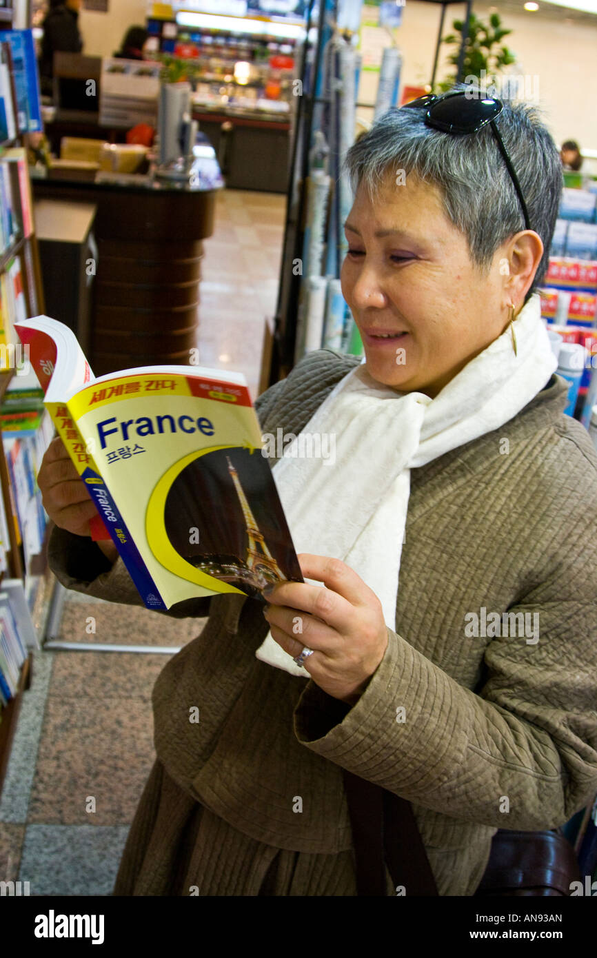 Donna coreana la lettura di una Francia la guida in una libreria Seoul COREA DEL SUD Foto Stock