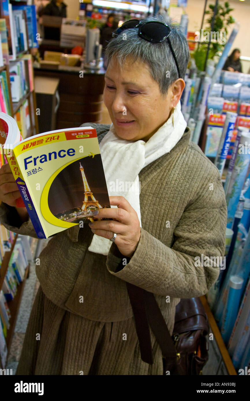 Donna coreana la lettura di una Francia la guida in una libreria Seoul COREA DEL SUD Foto Stock