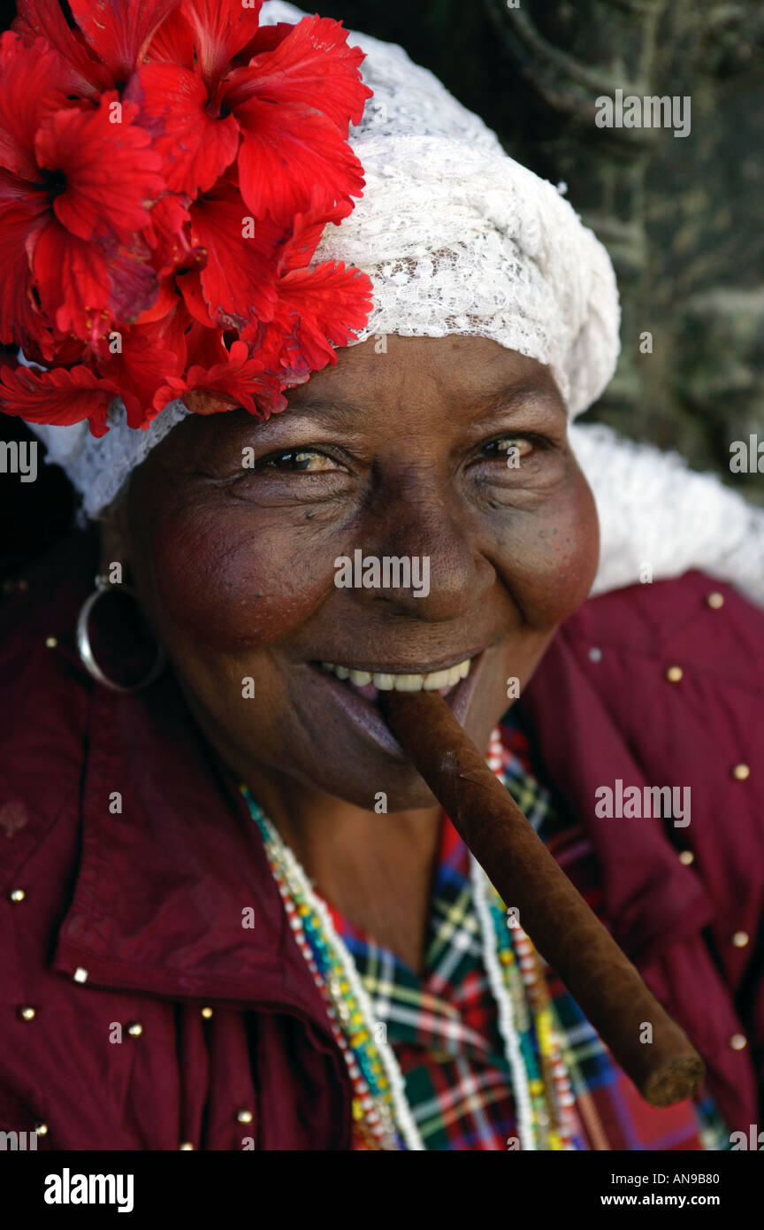 Un cubano signora vestita in costume tradizionale fuma un sigaro. Foto Stock