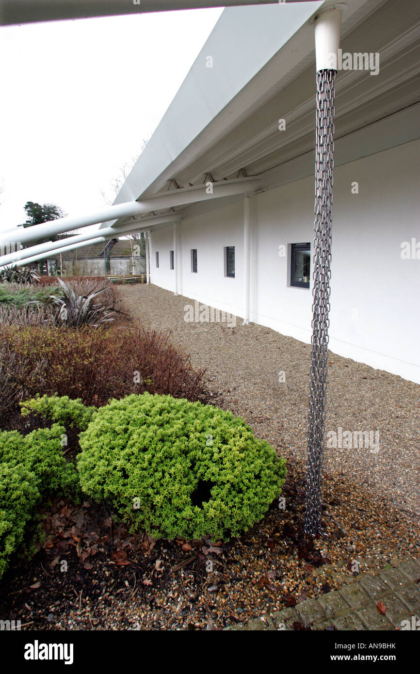 Le catene usate come percorsi di drenaggio per l'acqua piovana da sedum tetto di un edificio scolastico Foto Stock