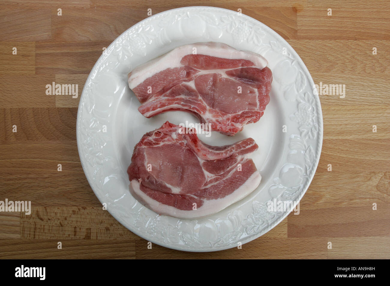Non cotte due costolette di maiale su di una piastra. Foto Stock