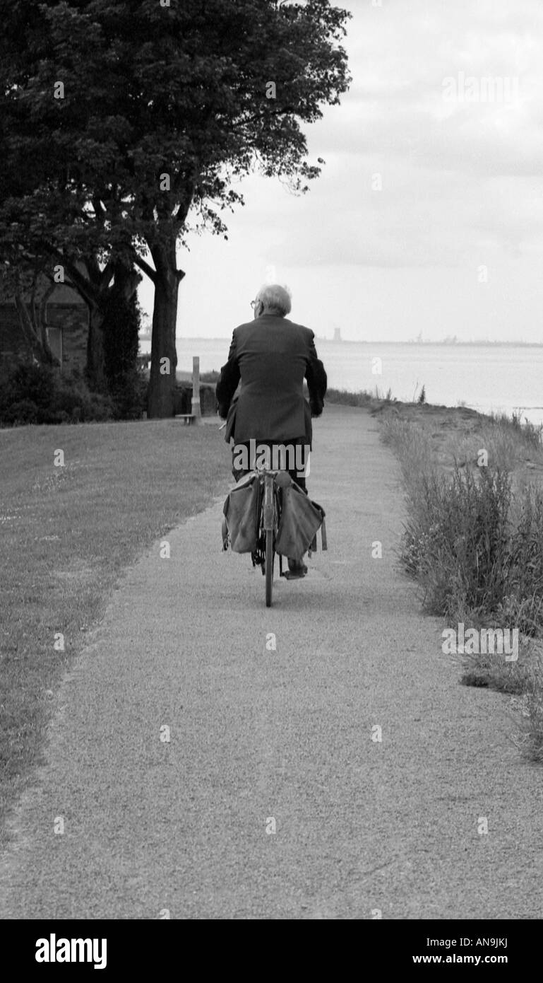 Il vecchio uomo bicicletta equitazione lungo il percorso con torna alla fotocamera. Foto Stock