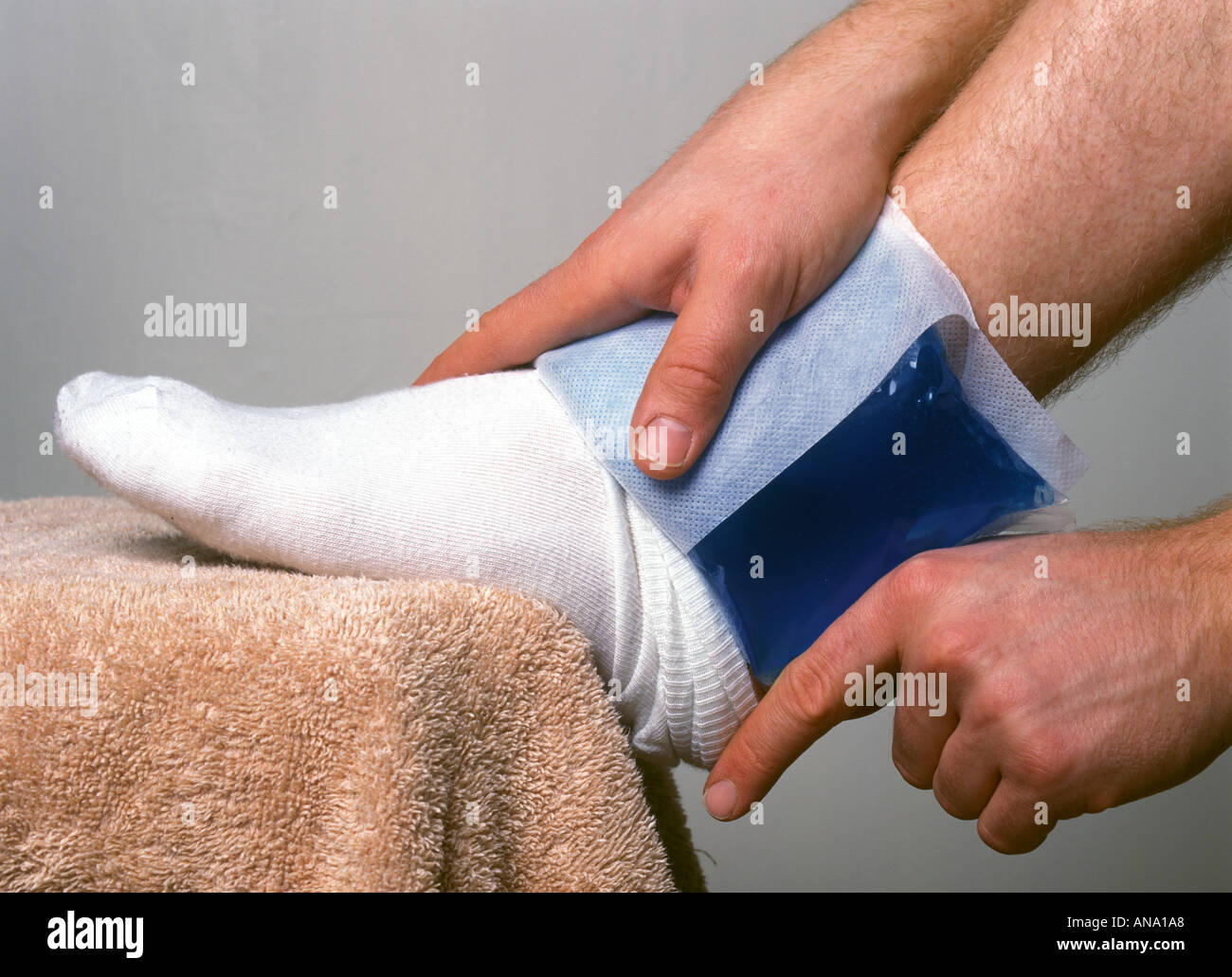 Riutilizzabili comprimere a freddo o gel pad essendo applicato alla caviglia maschio Foto Stock