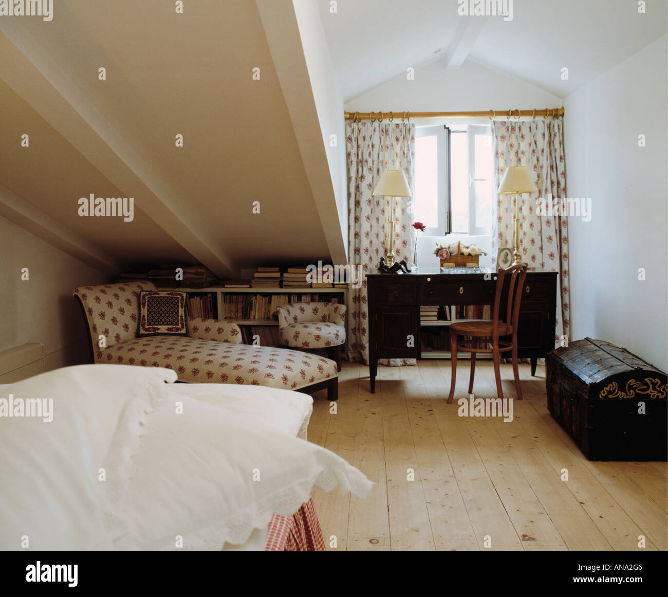 Tende a motivi geometrici e chaiselongue in mansarda camera da letto con pavimento in legno Foto Stock