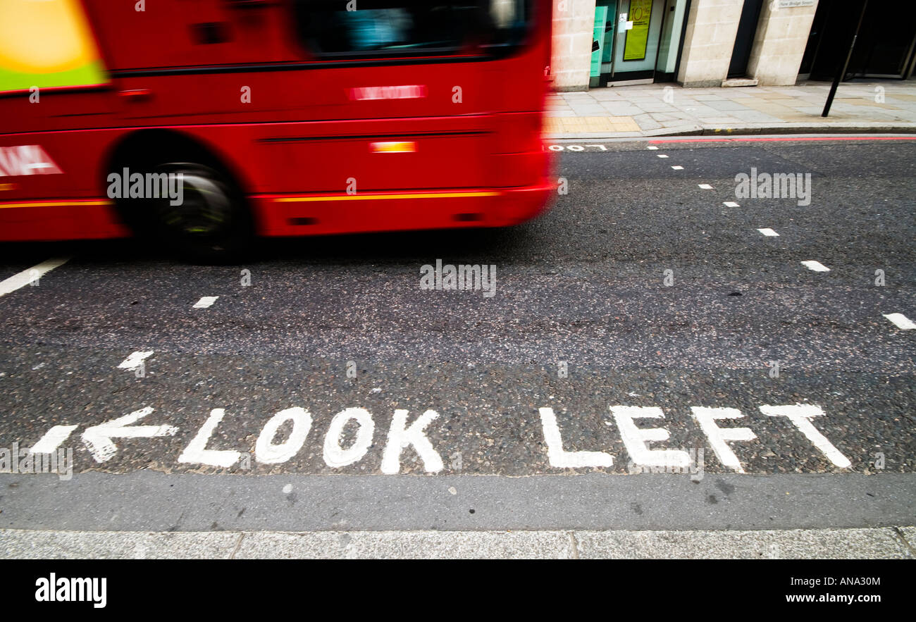 Attraversamento pedonale a guardare a sinistra e la sfocatura in movimento di un rosso double-decker bus in Londra Foto Stock