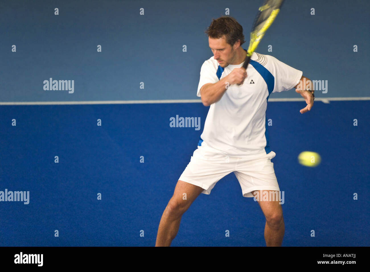 Uomo in bianco sportswear giocare tennis indoor Foto Stock