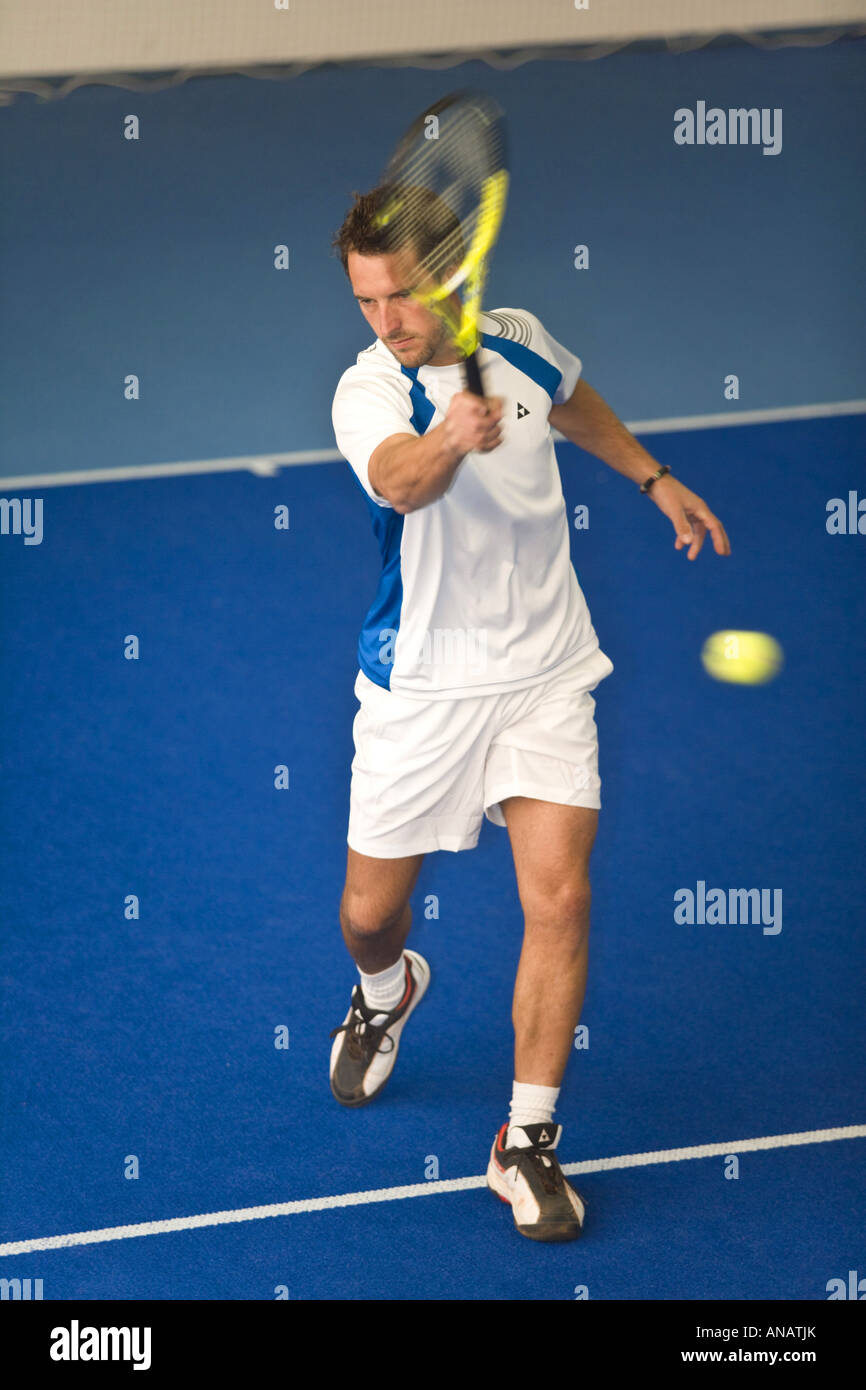 Uomo in bianco sportswear giocare tennis indoor Foto Stock