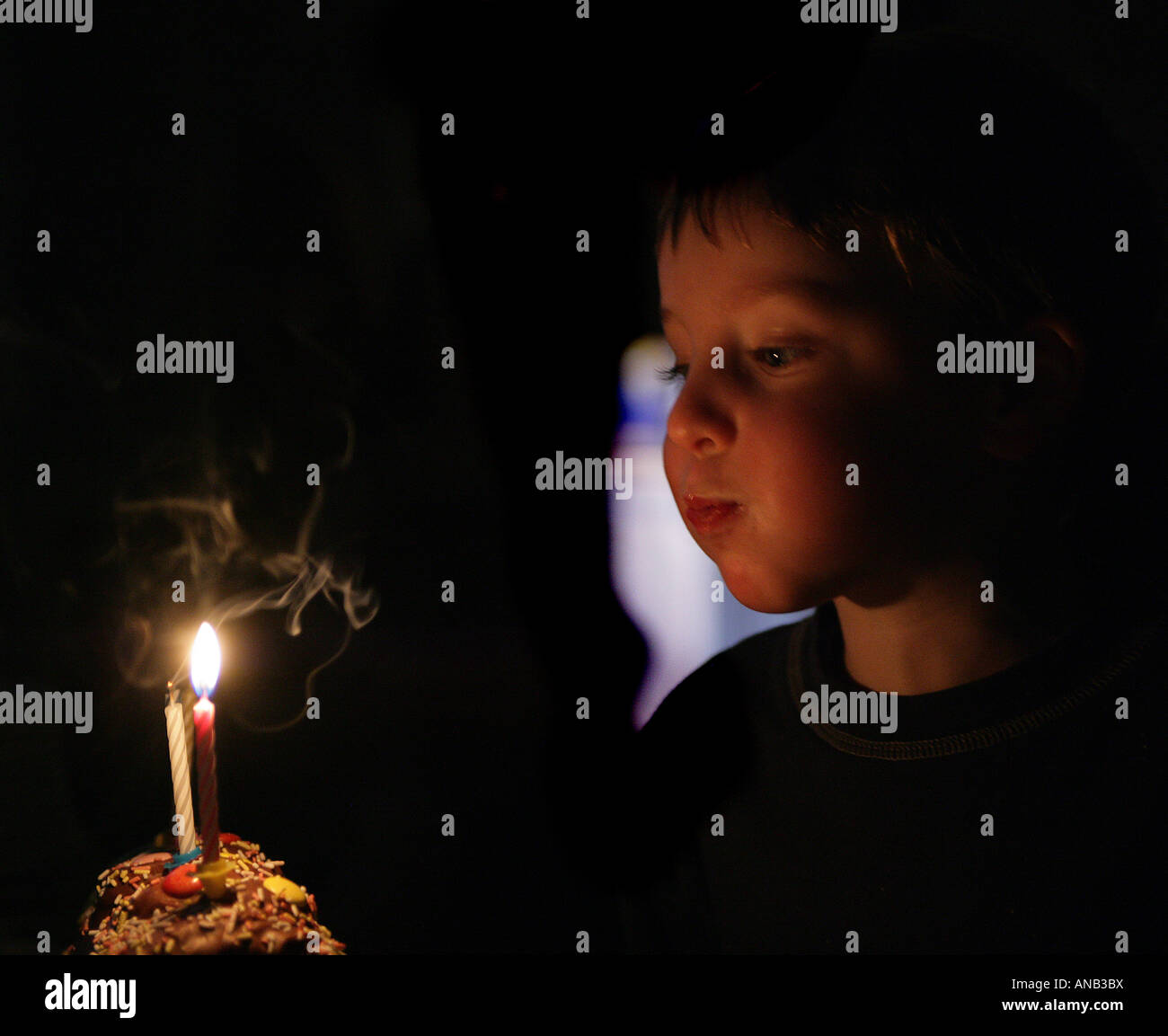 Bambino soffiando fuori candele su una torta di compleanno Foto Stock