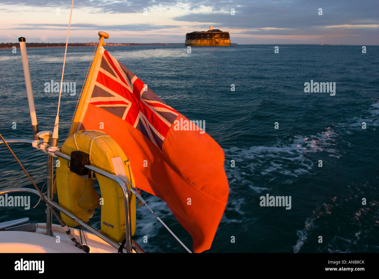 La poppa della barca con Red Ensign lasciando il Solent in mattina presto con No Man's Land Fort in background Foto Stock