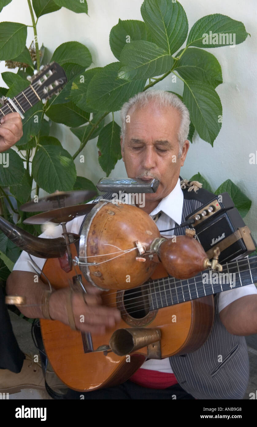 Uomo a suonare la chitarra (con erogatore di rum allegata) e armonica a bocca al Fiesta su Gran Canaria Foto Stock
