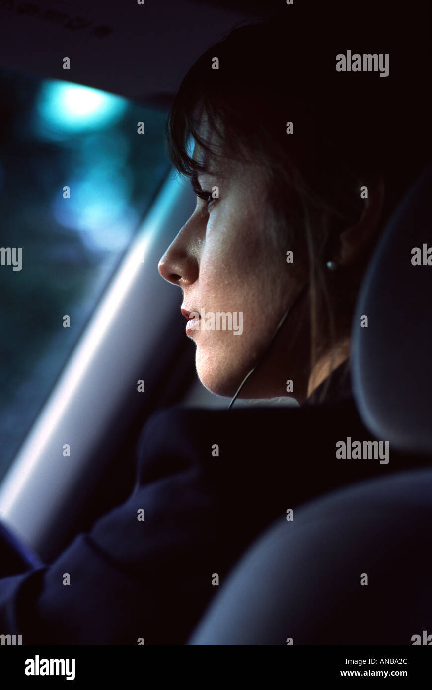 Azienda giovane donna alla guida di una vettura e indossando un telefono cellulare earpirce Foto Stock