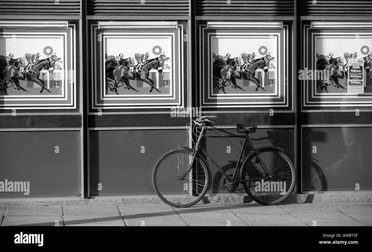 Vecchia bicicletta contro la parete esterna del negozio di scommesse Foto Stock