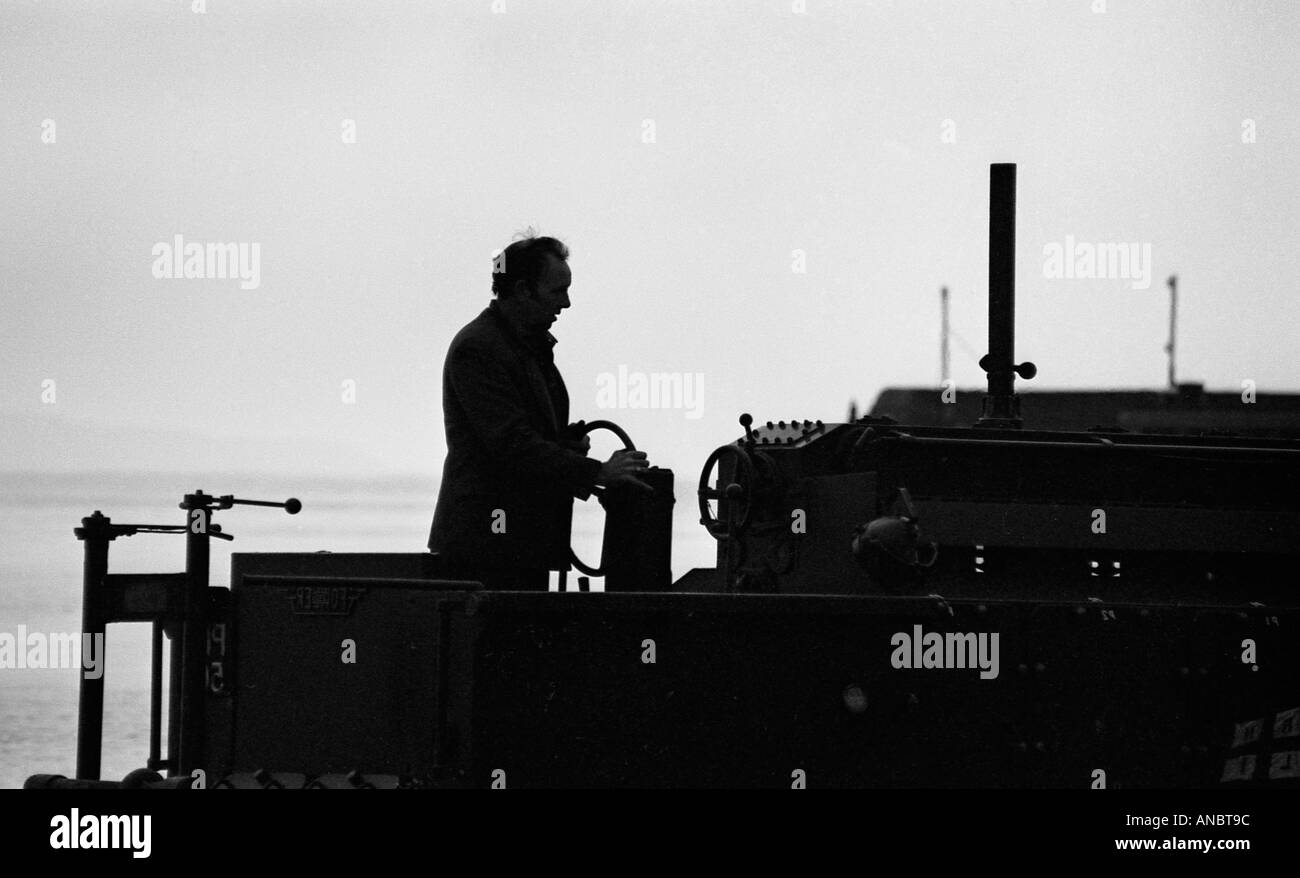 Uomo alla guida di vecchio trattore in silhouette Foto Stock