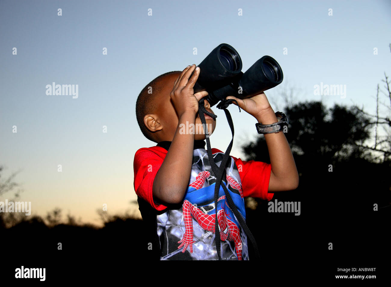 Motswana boy guardando attraverso il binocolo Foto Stock